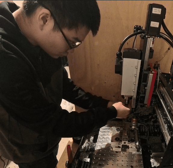 Founder in a small workshop next to a desktop CNC and laptop running NCLink